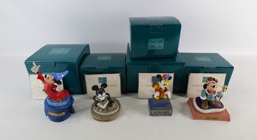 Four Disney figurines sit outside their boxes. They are limited edition.